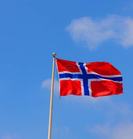 Téléchargez les photos : Drapeau national de la Norvège agitant dans le vent par temps clair. Champ rouge avec une croix bleue à contour blanc - en image libre de droit