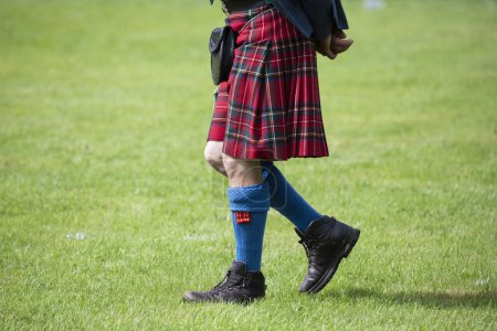 Photo for A Scottish Highland Games judge walks around the field wearing a red kilt in the town of Crieff - Royalty Free Image