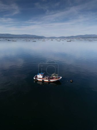 Ein kleines hölzernes Fischerboot, das in der Arousa-Mündung vor Anker liegt. Polygon der Muschelzucht