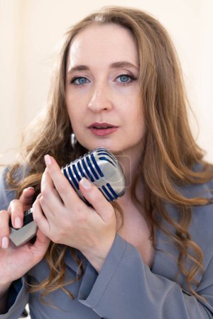 Foto de Retrato de una joven vocalista con un micrófono en las manos cerca del labio - Imagen libre de derechos