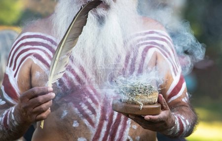 Téléchargez les photos : Cérémonie aborigène australienne de fumage, la main des hommes tient la fumée des plantes en feu, le rite rituel à l'événement communautaire, symbole de la culture et des traditions autochtones - en image libre de droit