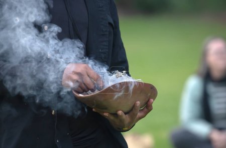 Téléchargez les photos : Des mains humaines tiennent un plat cérémonial en bois avec des branches fumées, le rituel d'accueil lors d'un événement communautaire autochtone en Australie - en image libre de droit