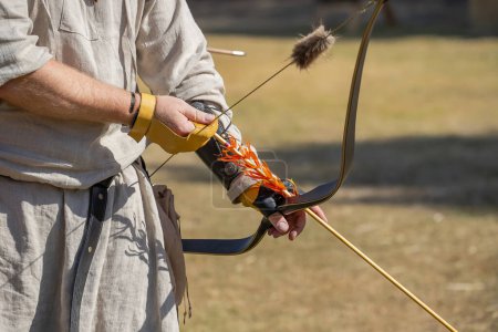 Photo for Medieval archery equipment, bow and arrow in the hands of a man. Medieval fair. High quality photo - Royalty Free Image