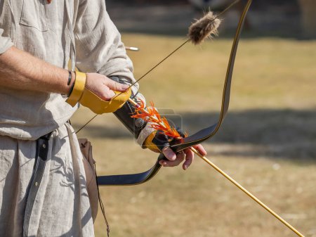 Medieval archery equipment, bow and arrow in the hands of a man. Medieval fair. High quality photo
