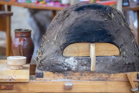 Keramikkrug, Schüssel mit Mehl und mittelalterlichem Lehmofen zum Brotbacken in Nahaufnahme, Geschirr auf Holztisch, mittelalterlicher Lebensstil, Stillleben. 