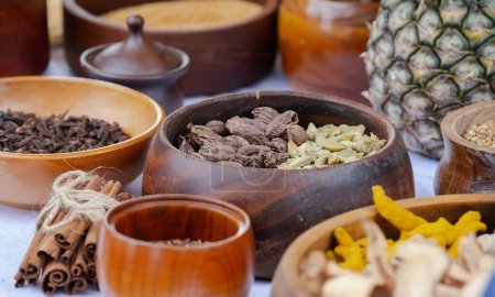 Wooden bowls with spices, cinnamon, cardamom, cloves, nutmeg, close up, ceramics on a wooden table, focus on one bowl, still life. High quality photo