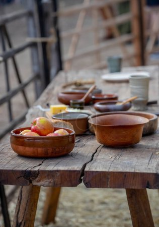 Manzanas maduras en un tazón de cerámica de cerca, cerámica sobre una mesa de madera, estilo de vida medieval, naturaleza muerta. Foto de alta calidad