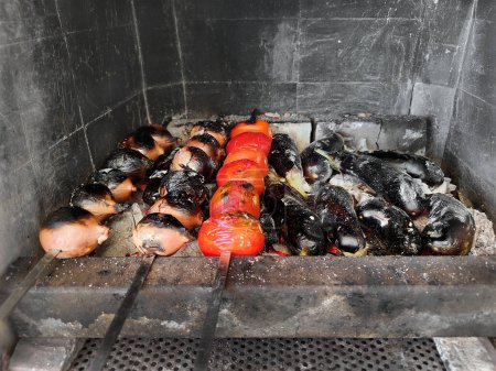Photo for Vegetables on skewers are fried on coals. Onions, tomatoes, grilled eggplant. Picnic - Royalty Free Image