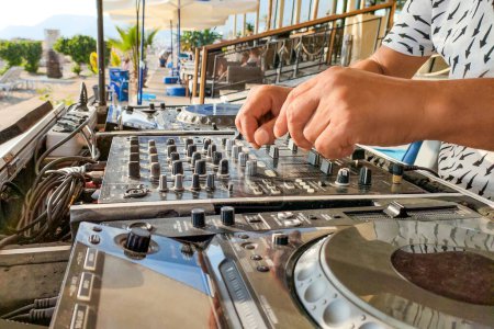 Turkey, Alanya - August 12, 2022: DJ plays on dj console mixer on beach, hands and turntable close-up