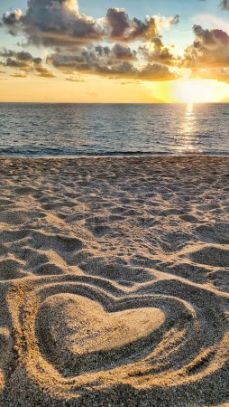 Photo for Heart made of sand on beach against background of sea and beautiful sunset, in rays of sun, concept of love and health - Royalty Free Image