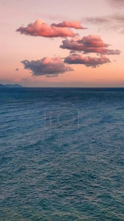 Photo for Pink clouds in evening sky over blue sea, twilight fabulous sunset, copy space, vertical frame - Royalty Free Image