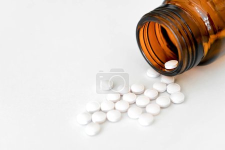 Medikamente in Nahaufnahme: Weiße Pillen und braune Glasflaschen auf dem Tisch, Kopierraum, Nahaufnahme, Gesundheitskonzept..