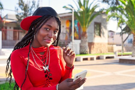 Téléchargez les photos : Portrait noir souriant adolescent fille assis sur la rue - en image libre de droit