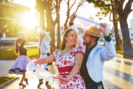 small group of Latin American young adults dressed as huaso dancing cueca in the town square at sunset