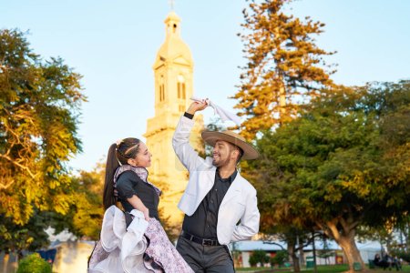 Taille nach oben Portrait junge erwachsene lateinamerikanische Paar tanzt Cueca Nationaltanz mit Huaso-Kleid auf dem Stadtplatz von La Serena