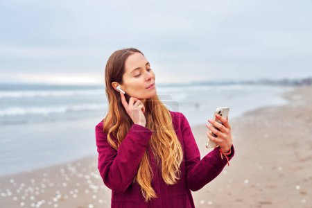 portrait beautiful caucasian woman listening to music on the beach