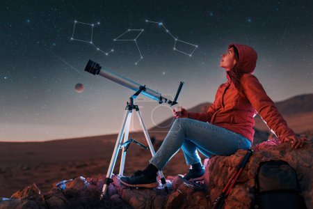 portrait femme assise dans le désert seule à côté d'un télescope la nuit regardant les constellations sur le ciel étoilé, cartographie du ciel ou concept de carte des étoiles