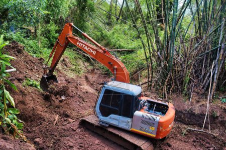 Téléchargez les photos : Excavatrice approfondissant un lit de rivière sec à travers une forêt de bambous dans la province de Phetchabun, Thaïlande. mai 12, 2023 - en image libre de droit