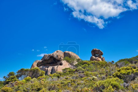 Photo for Granitic rock formation with balancing rock rising up from the coastal vegetation in Cape Le Grand National Park, Western Australia. - Royalty Free Image