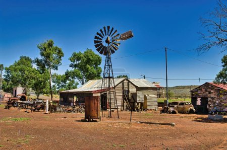 Téléchargez les photos : Maison en fer ondulé, vieilles voitures rouillées et un moulin à vent dans la ville fantôme de Gwalia dans le Grand Désert de Victoria, shire de Leonora, Australie occidentale - en image libre de droit