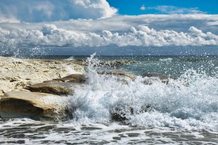 Téléchargez les photos : Des vagues s'écrasent sur une côte rocheuse. Paysage nuageux impressionnant avec nuages orageux menaçants et ciel bleu. Côte sud de Chypre. - en image libre de droit