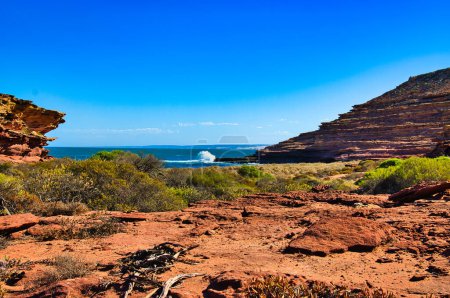 Téléchargez les photos : Petite plage avec végétation résistante à la sécheresse, bordée de falaises de grès rouge érodées, à l'embouchure du canyon aride Eagle, parc national de Kalbarri, Australie occidentale. - en image libre de droit