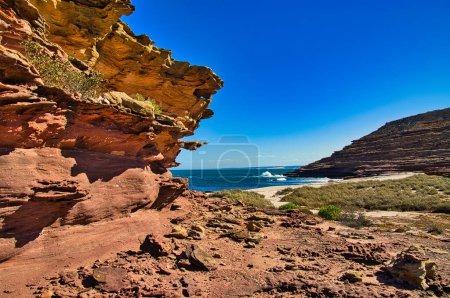 Téléchargez les photos : Vagues se brisant sur une plage déserte, bordée de rochers de grès sombres et stratifiés. Bouche du canyon Eagle, parc national de Kalbarri, Australie-Occidentale. - en image libre de droit