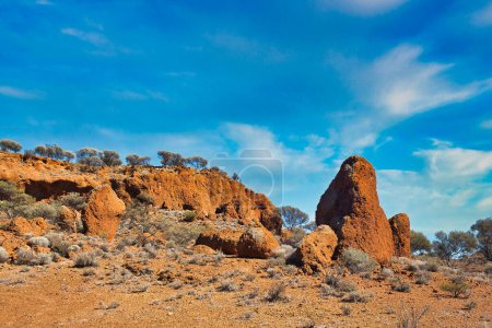 Formations rocheuses de latérite rouge et végétation résistante à la sécheresse dans l'arrière-pays australien, à proximité du mont Magnet, Australie occidentale.