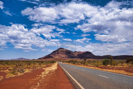 Highway im abgelegenen Wüsten-Outback des Karijini National Park, Westaustralien. Blick auf Mount Bruce, den zweithöchsten Berg Westaustraliens