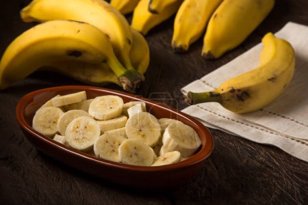 Foto de Manojo de plátanos con plátanos en rodajas sobre la mesa. - Imagen libre de derechos