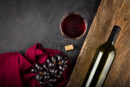 Foto de Copa de vino tinto y una botella de vino con uvas frescas en la mesa. - Imagen libre de derechos