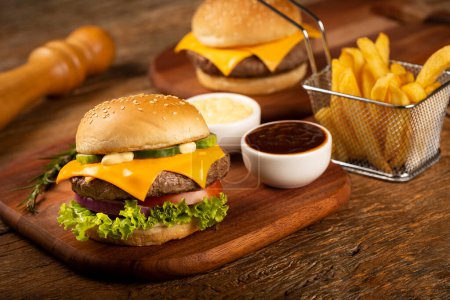 Foto de Hamburguesa, hamburguesa de queso con salsas y papas fritas. - Imagen libre de derechos
