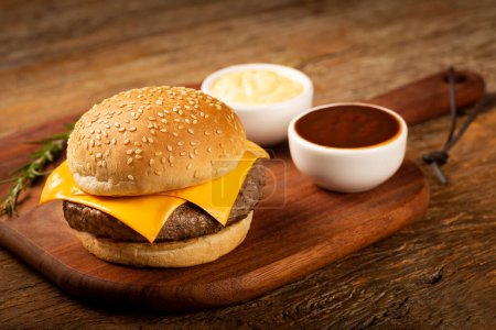 Foto de Hamburguesa con queso y salsas en la mesa. - Imagen libre de derechos