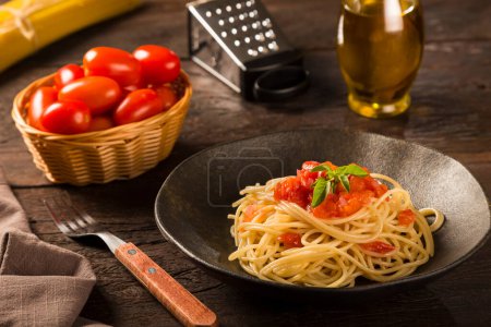 Dish with spaghetti in tomato sauce and basil.
