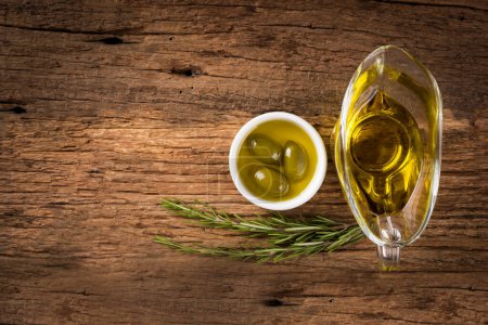 Téléchargez les photos : Bol à l'huile d'olive vierge sur fond bois rustique. - en image libre de droit