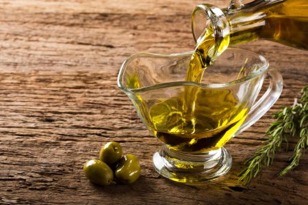 Photo for Bottle pouring virgin olive oil into a bowl. - Royalty Free Image