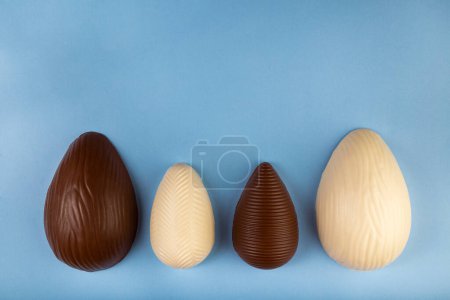 Téléchargez les photos : Pâques. Composition avec œufs de Pâques en chocolat sur fond bleu, espace pour le texte. - en image libre de droit