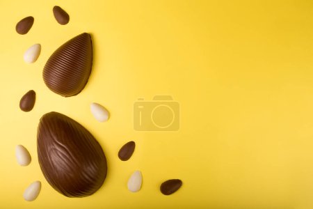 Téléchargez les photos : Pâques. Composition avec œufs de Pâques en chocolat sur fond jaune, espace pour le texte. - en image libre de droit