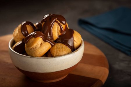 Delicious profiteroles with coffee on the table.