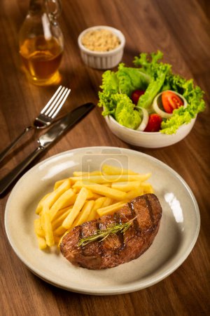 Téléchargez les photos : Plat avec steak grillé, frites et salade. - en image libre de droit