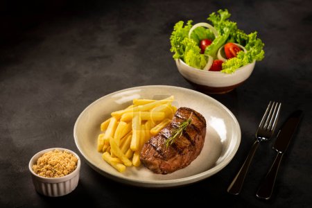 Photo for Dish with grilled steak, French fries and salad. - Royalty Free Image