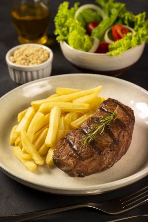Téléchargez les photos : Plat avec steak grillé, frites et salade. - en image libre de droit