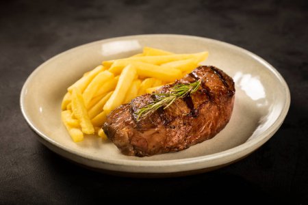 Téléchargez les photos : Plat avec steak grillé et frites. - en image libre de droit