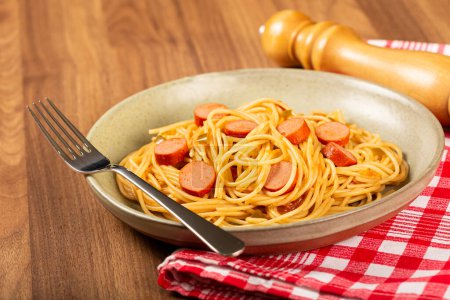 Foto de Pasta de espaguetis con salchichas en rodajas y salsa de tomate. - Imagen libre de derechos