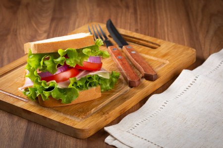 Foto de Sandwich natural. Sandwich con queso, jamón, lechuga, tomate y cebolla roja. - Imagen libre de derechos