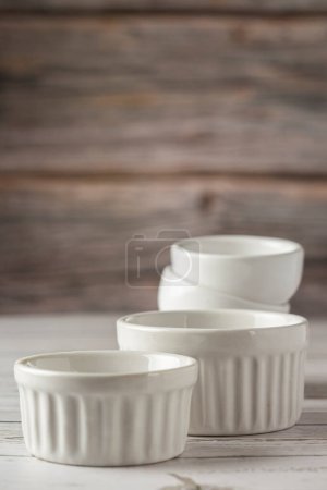 Photo for Bowls and ramekins on the table on the wooden background. - Royalty Free Image