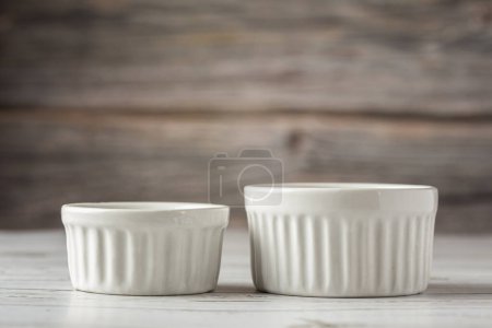 Photo for Bowls and ramekins on the table on the wooden background. - Royalty Free Image