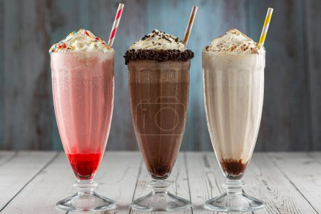 Photo for Three glasses of milkshake with assorted flavors. Chocolate, vanilla and strawberry milkshake. - Royalty Free Image
