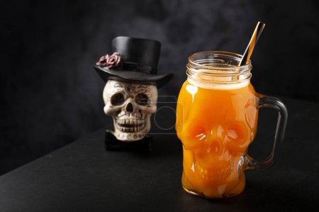 Halloween drink. Pumpkin drink in skull glass. Stickers 709773196
