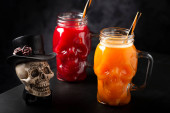 Halloween drink. Pumpkin drink and blood drink in skull glass. t-shirt #709773208